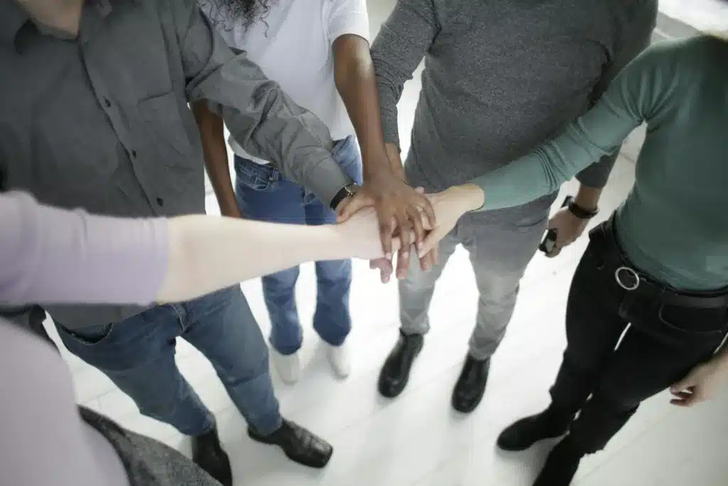 From above of faceless diverse coworkers wearing casual outfits stacking hands together while gathering in modern office at daytime. Stress relief strategies, busy professional 