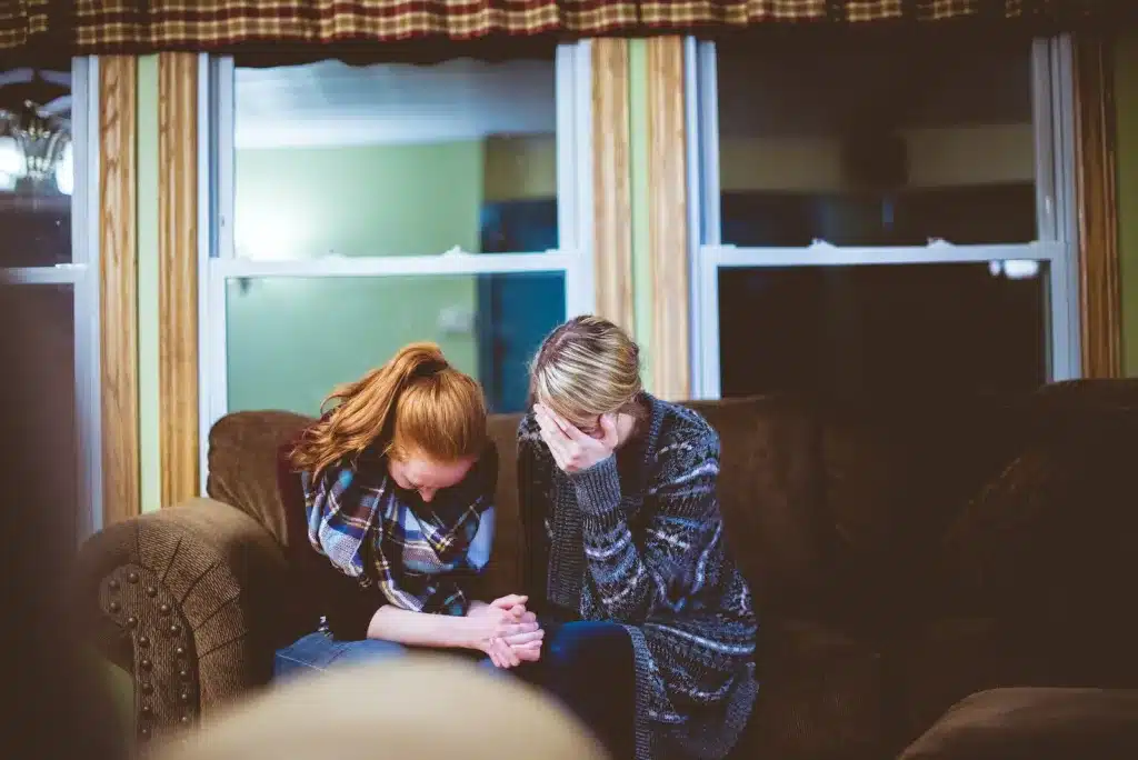 man and woman sitting on sofa in a room. helping a grieving friend or supporting a friend through grief.